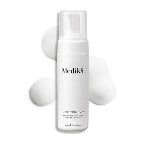 Flacon-pompe Medik8 Clarifying Foam présenté sur un fond blanc propre avec trois petites touffes de mousse blanche aérienne. Le texte l'identifie comme un Refreshing AHA/BHA Blemish Cleanser de 150 mL