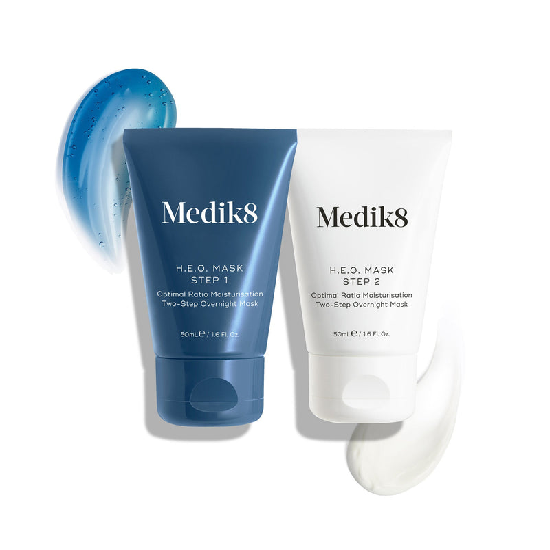 Un carton d'emballage blanc pour le masque H.E.O. est posé à côté de deux tubes du masque.
