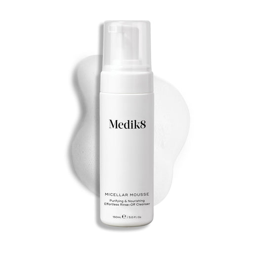 Flacon-pompe Medik8 Micellar Mousse présenté sur un fond blanc avec une trace de mousse blanche derrière, mettant en valeur la texture du produit.