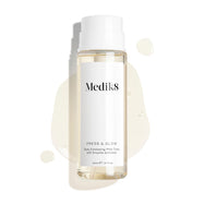 Flacon Medik8 Press & Glow – placé sur un fond blanc épuré avec des gouttes de liquide translucides et une petite flaque, mettant en valeur sa texture aqueuse. Le texte identifie le produit comme un tonique exfoliant quotidien PHA de 200 mL avec activateur enzymatique.