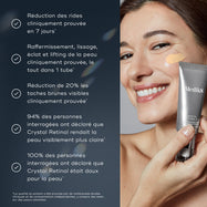 Une femme à la peau éclatante et nette sourit vivement tout en appliquant délicatement une petite quantité de Medik8 Crystal Retinal d'un tube argenté sur sa joue. Le produit a une teinte jaune pâle. Des points à puces en allemand sur la gauche décrivent les bienfaits du produit.